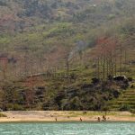 A picturesque riverside scene featuring tourists enjoying the serene landscape in Vietnam.